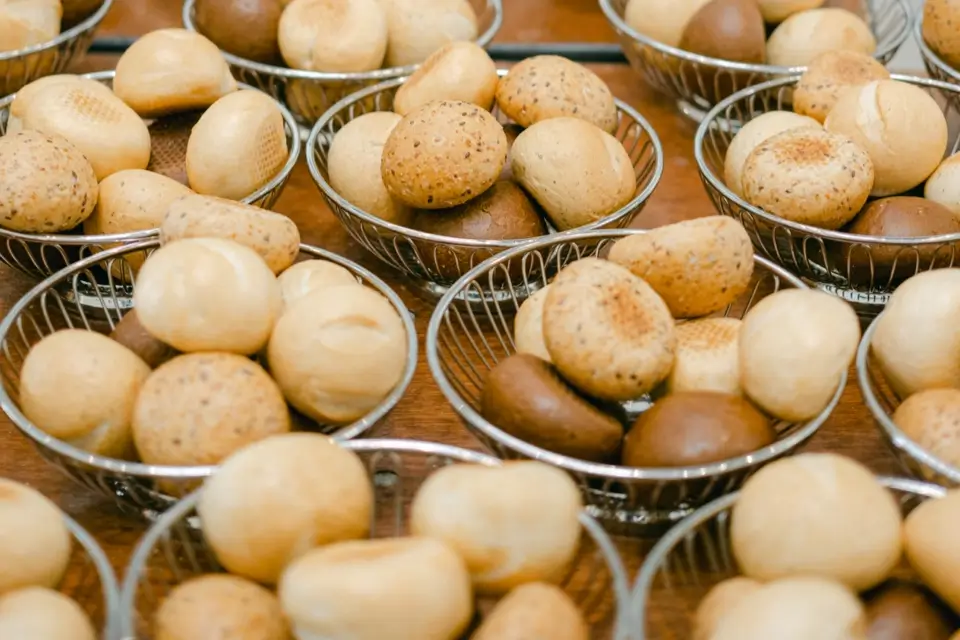 Baskets filled with various types of small, round bread rolls, some with speckled and others with smooth, shiny surfaces, are arranged on a wooden table. 124 on Queen Hotel and Spa | Hotel & Spa Niagara-on-the-lake | 1 (855) 988-4552